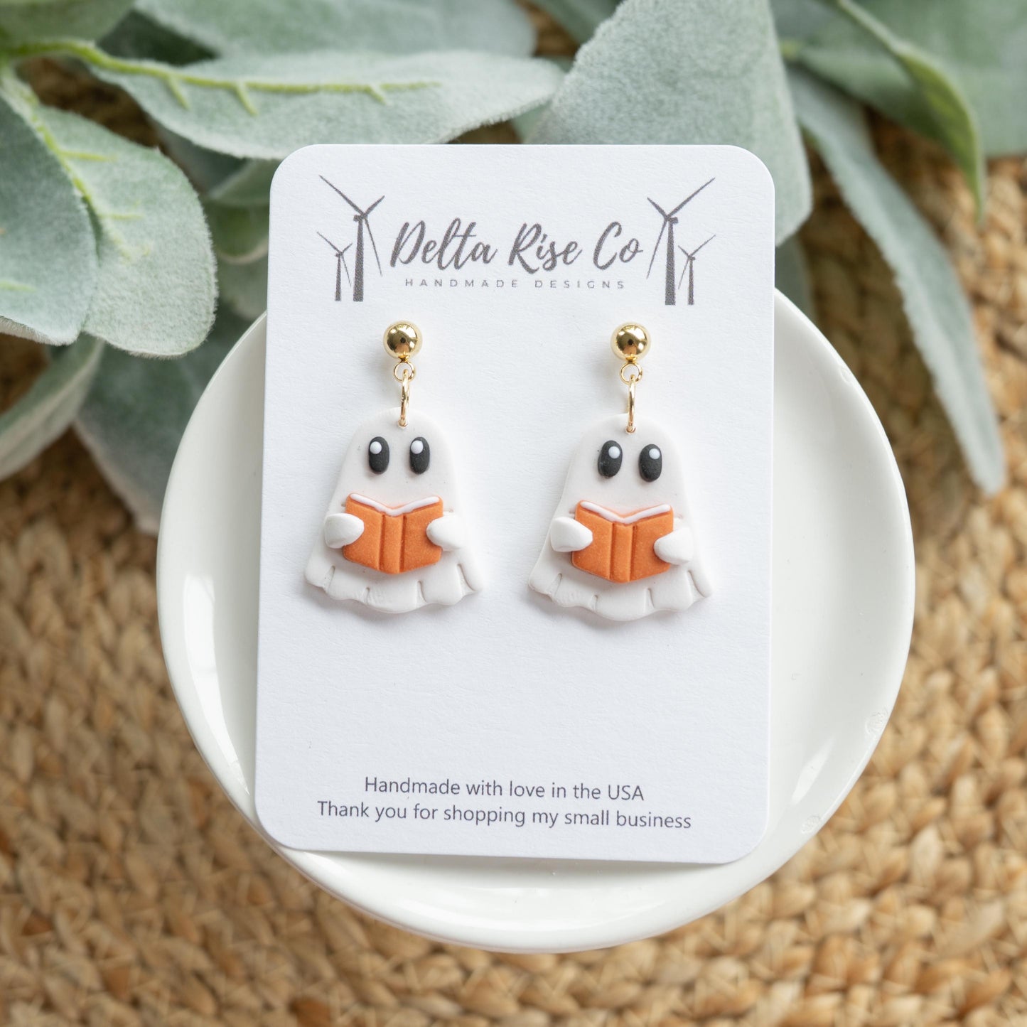 Handmade ghost earrings featuring a cute white ghost reading an orange book, perfect for Halloween and fall fashion. These lightweight polymer clay earrings combine spooky charm with bookish style, making them ideal for seasonal outfits, festive parties, or gifts for book lovers. Unique Halloween jewelry that’s comfortable to wear and designed to bring a fun, whimsical touch to your autumn accessories.