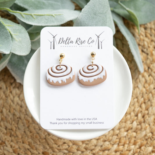 Handmade polymer clay cinnamon bun roll earrings, perfect for dessert lovers and fall fashion. Lightweight and whimsical, these earrings feature a realistic cinnamon swirl design, making them a fun accessory for everyday wear or festive autumn outfits. Unique handmade food-inspired jewelry ideal for gifting, statement looks, or adding a cozy, sweet touch to seasonal fashion.