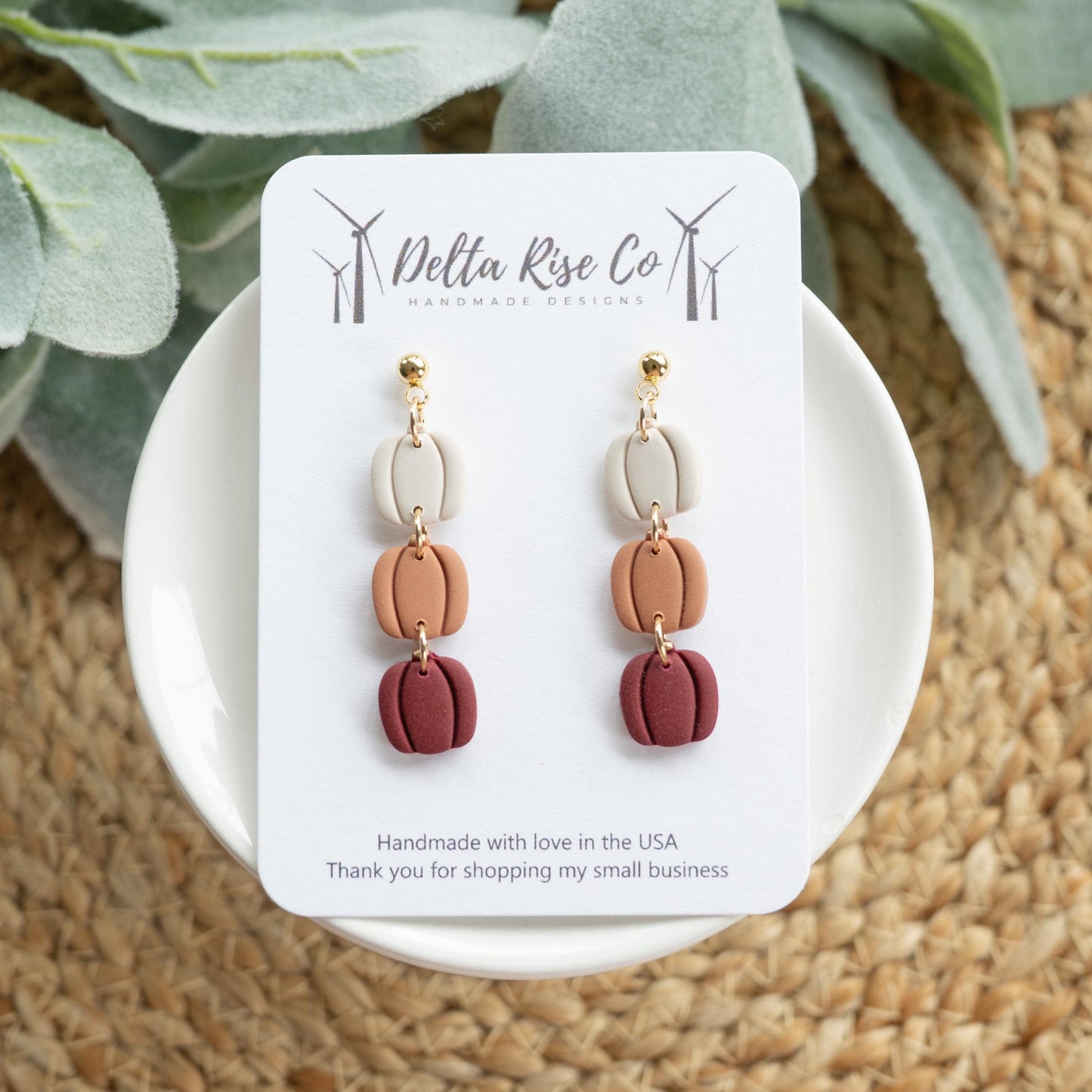 Handmade triple pumpkin earrings in cream, pumpkin orange, and maroon, perfect for fall and autumn fashion. Lightweight polymer clay earrings feature three stacked pumpkins with a layered design, adding festive charm and seasonal style to Thanksgiving outfits, autumn events, or pumpkin patch visits. Comfortable, whimsical, and unique handmade jewelry for lovers of fall-inspired accessories.