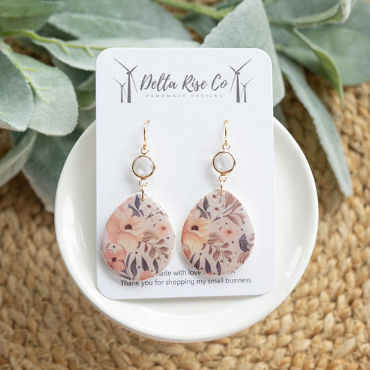 Handmade floral earrings with glass charm connector, perfect for boho, statement, and seasonal fashion. Lightweight polymer clay earrings feature intricate floral designs paired with a sparkling glass charm, adding elegance and charm to casual or festive outfits. Unique handmade jewelry ideal for gifting, layering with other accessories, or adding a delicate touch to any wardrobe.